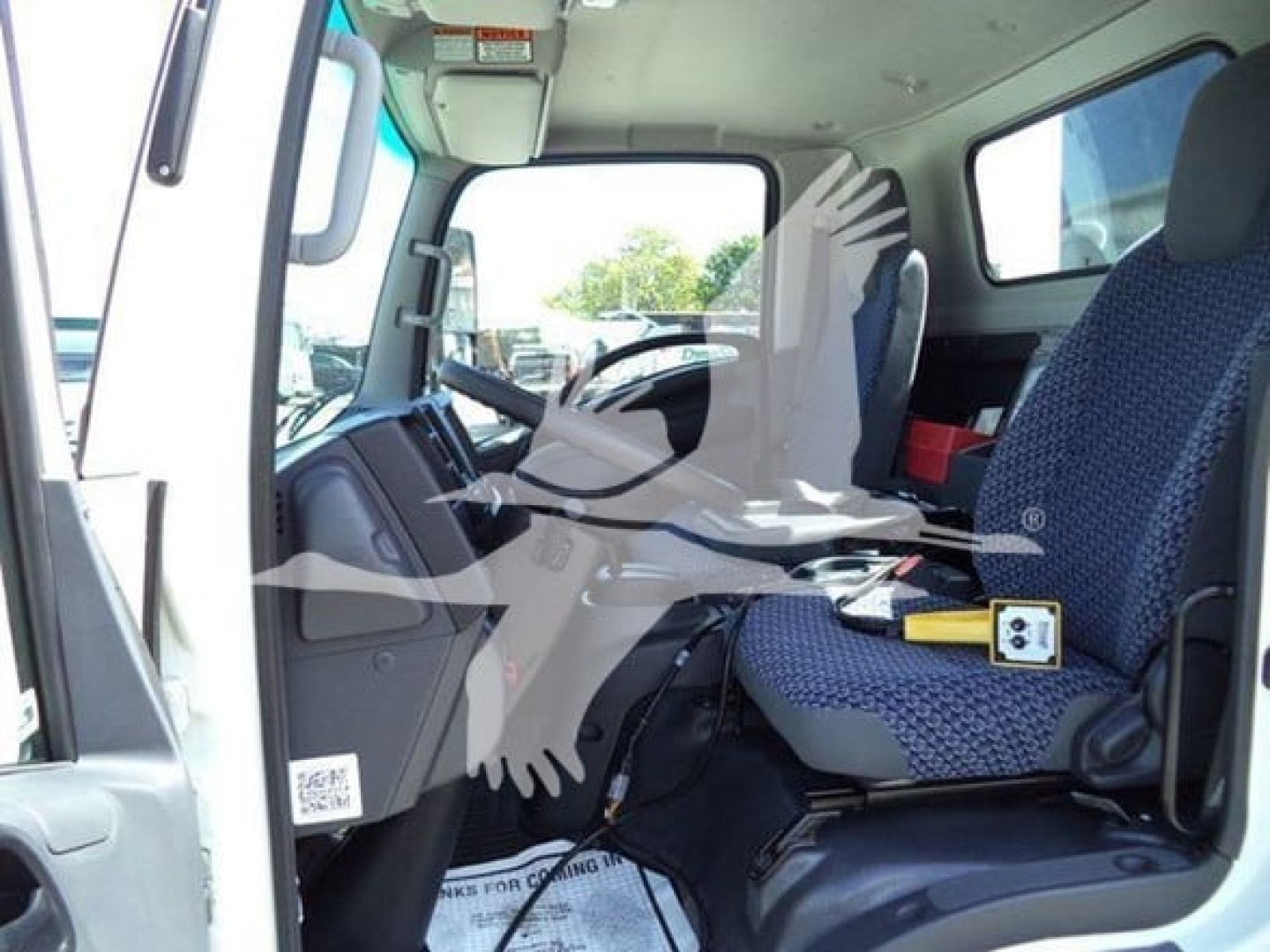 Isuzu NPR-HD truck cabin interior showing driver seat and passenger seat with steering wheel and dashboard.