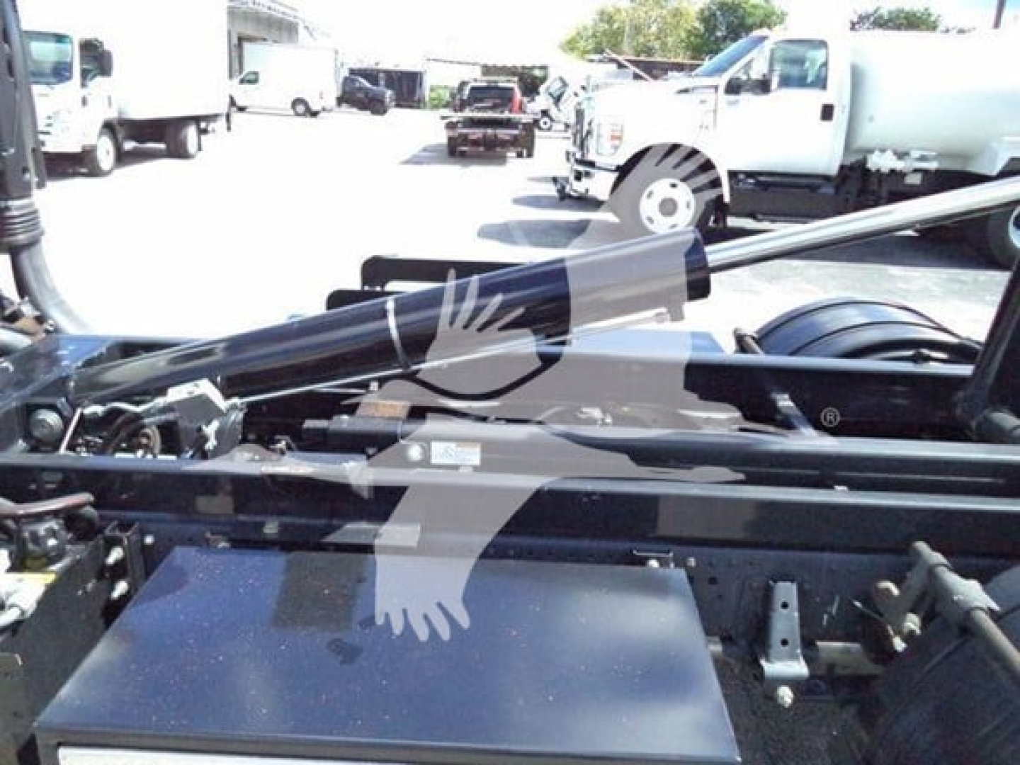 Isuzu NPR-HD truck chassis showing hydraulic hooklift arms and transmission area with various components.