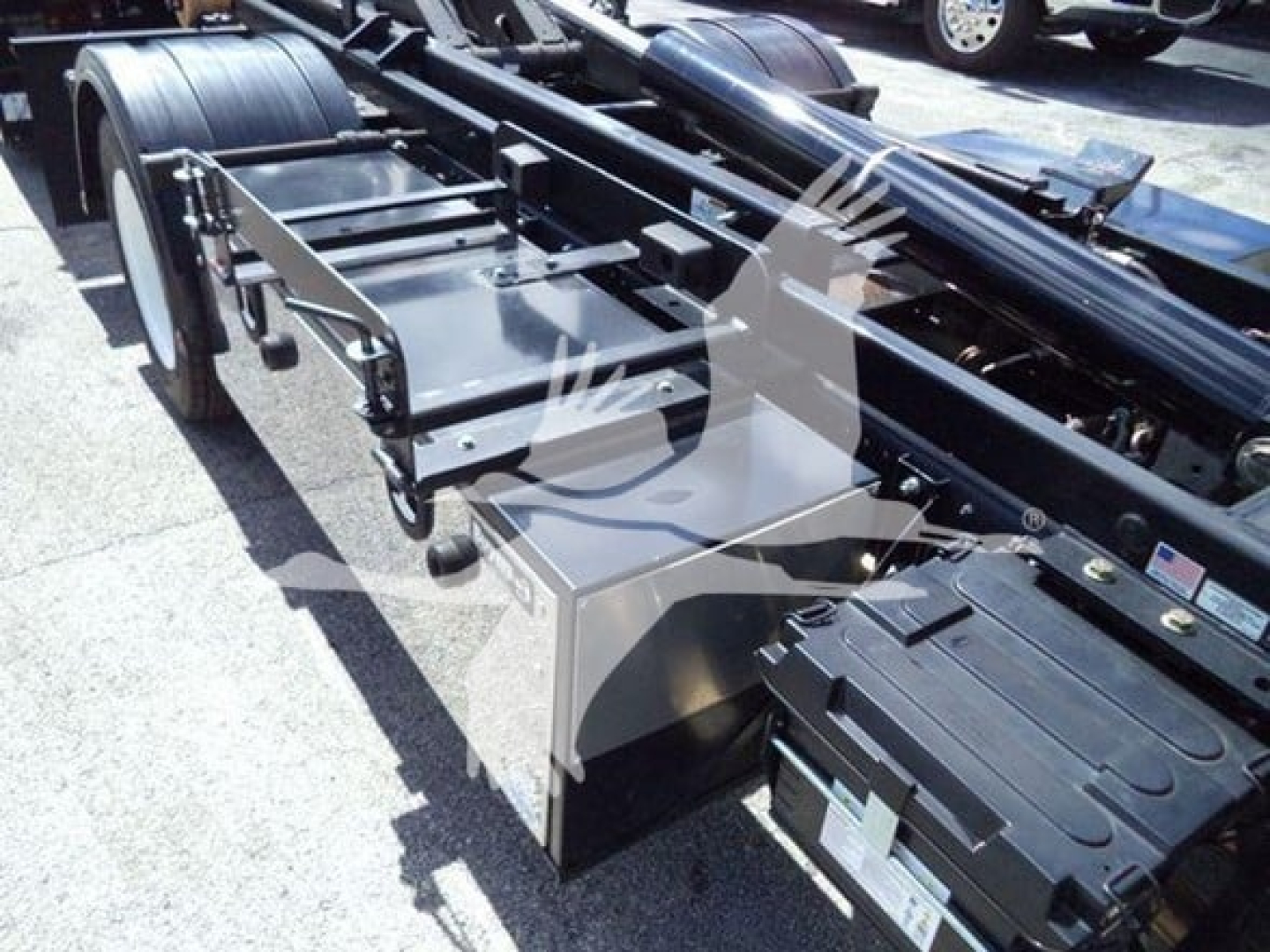 Isuzu NPR-HD truck chassis frame showing hooklift bed and toolbox with panels and hydraulic components.