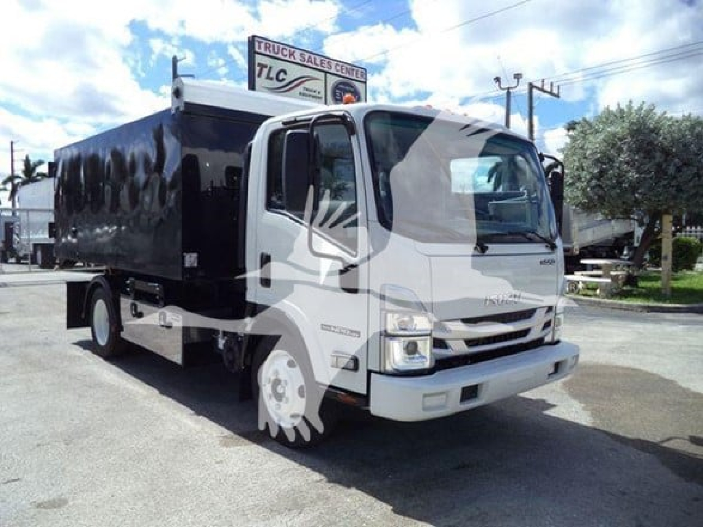 Isuzu NPR-HD truck with black hooklift body, front view showing cab and cargo area.