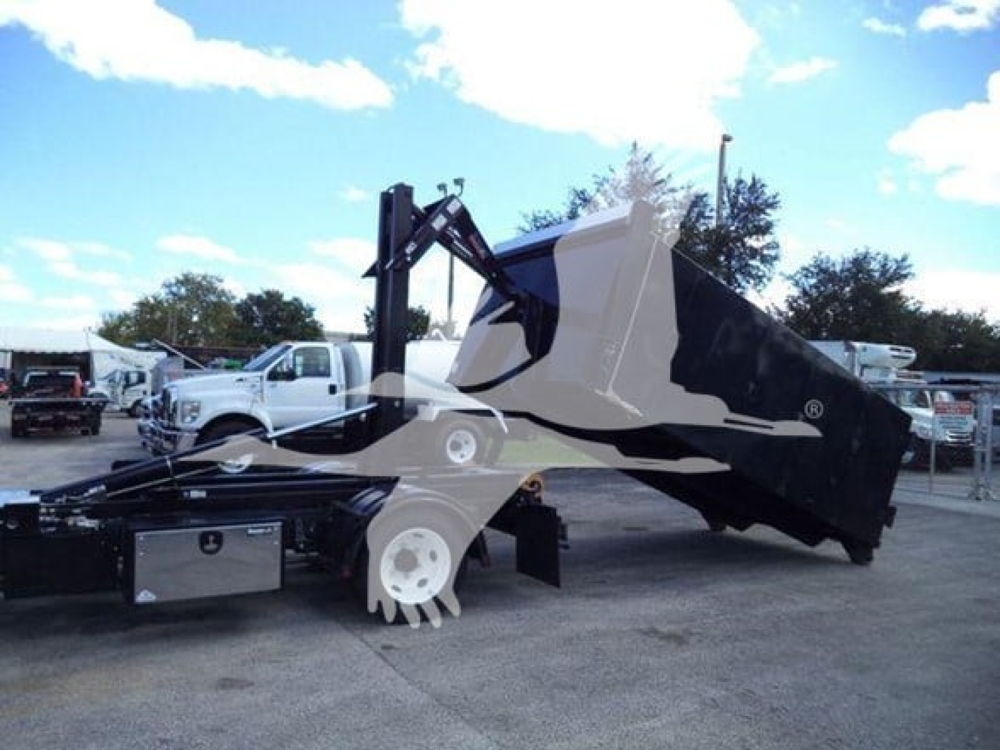 Isuzu NPR-HD hooklift truck with hydraulic lifting arm and empty dumped bin attached, side view in dealership lot.