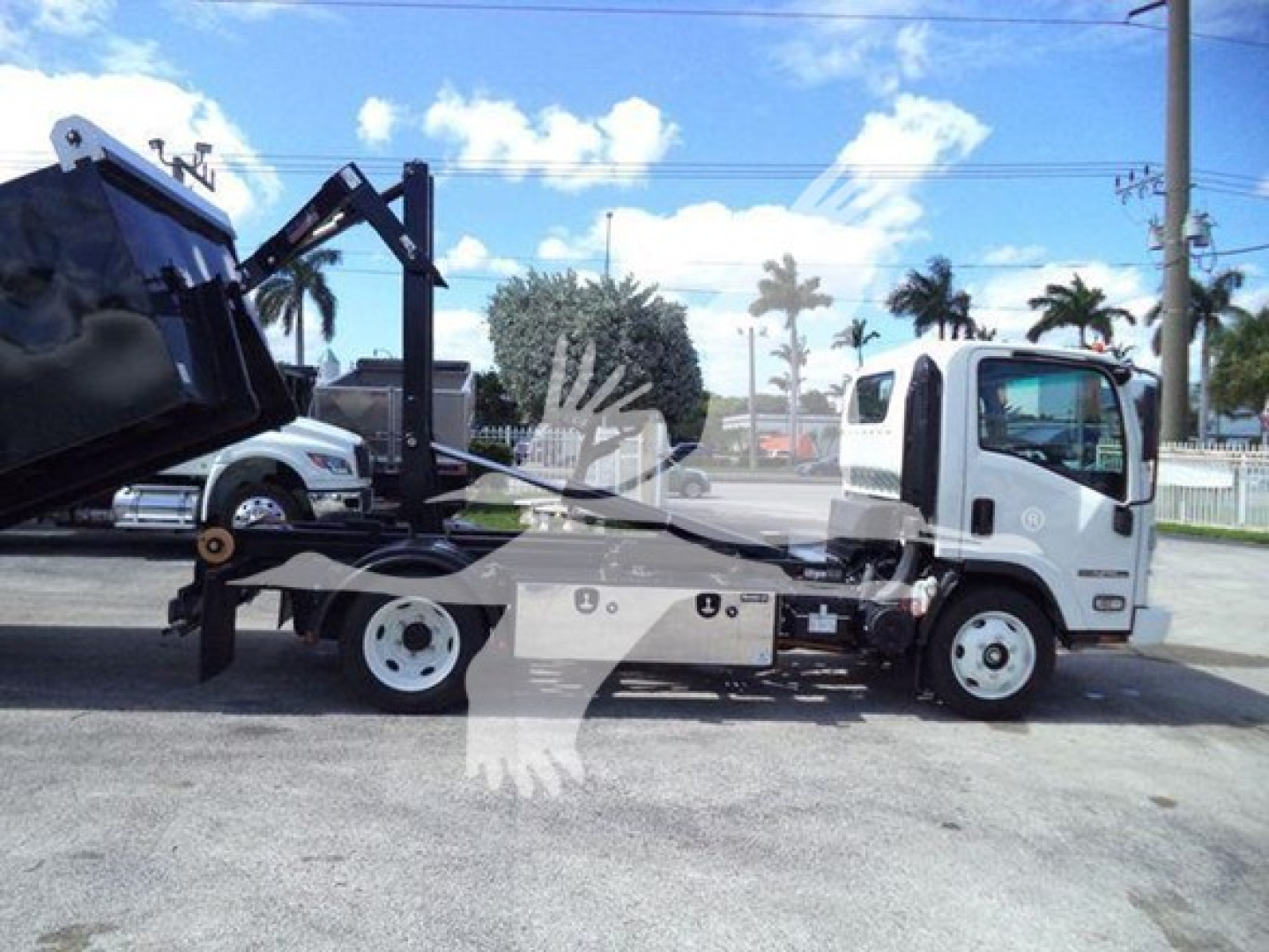 Isuzu NPR-HD hooklift truck side view showing cab, wheel, and chassis with hooklift bed and hydraulic system.