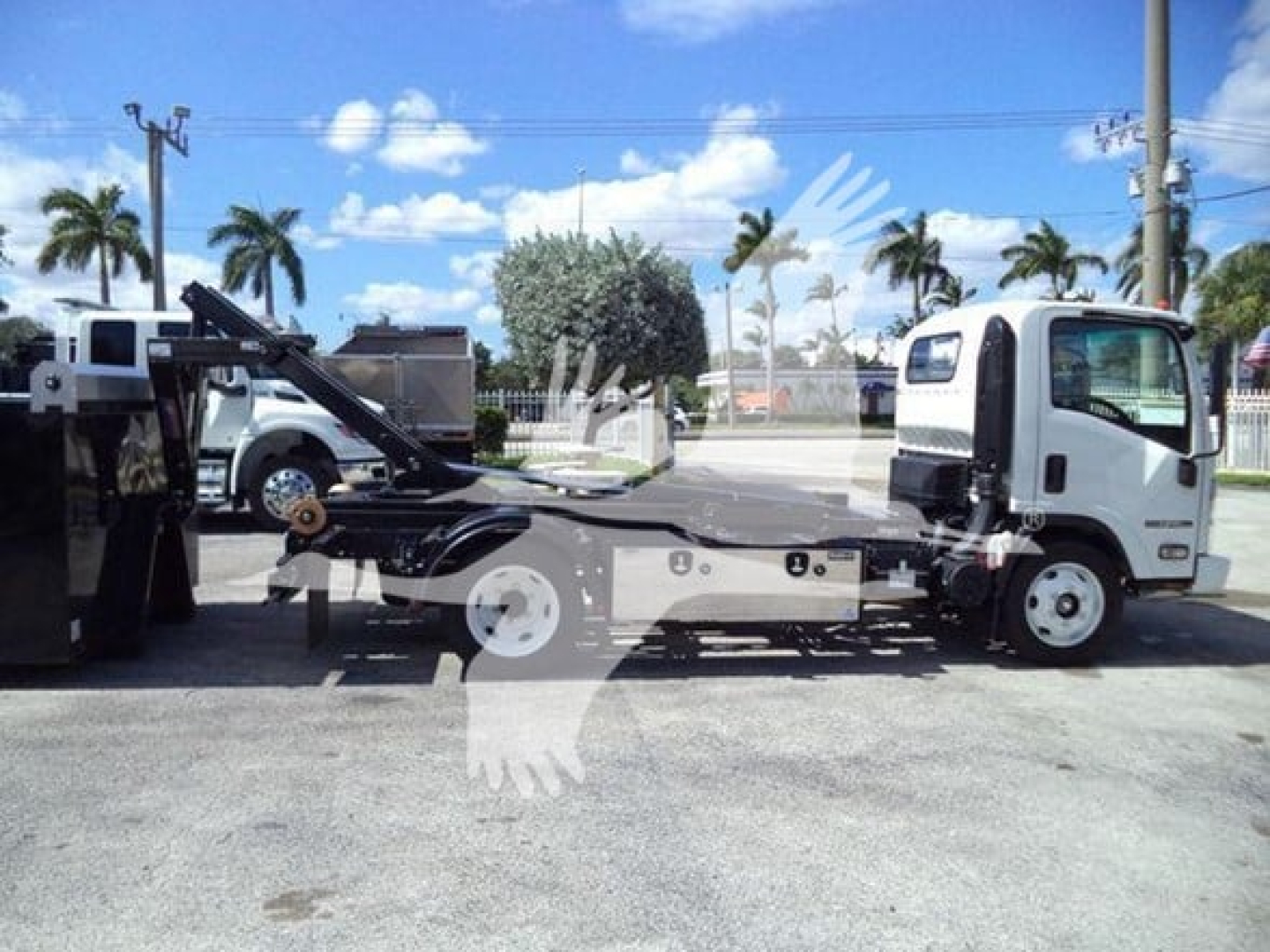 Isuzu NPR-HD tow truck with hooklift body side view showing cab and flatbed hoist mechanism.