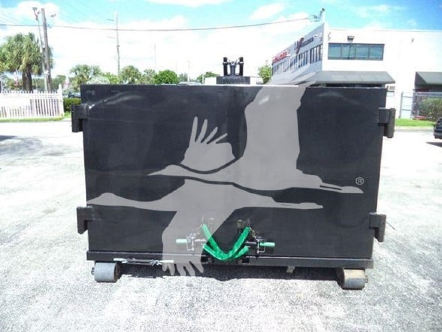 Isuzu NPR HD truck component showing a black waste body with a green hitch attachment and white graphic of a bird in flight.