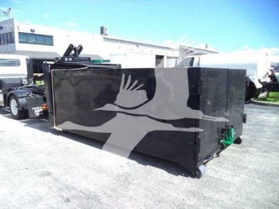 Isuzu NPR HD category truck or equipment in a lot showing a large black hopper/toolbox with green fittings on the side and wheel feet.