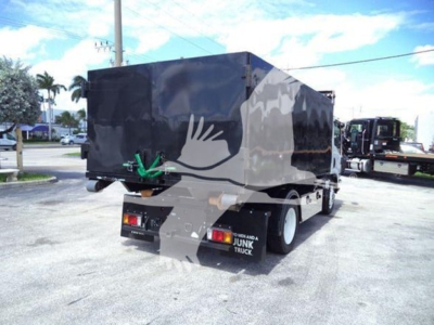 Isuzu NPR HD truck with a dark cargo box seen from rear-left, showing rear bumper lights and a green towing hook.