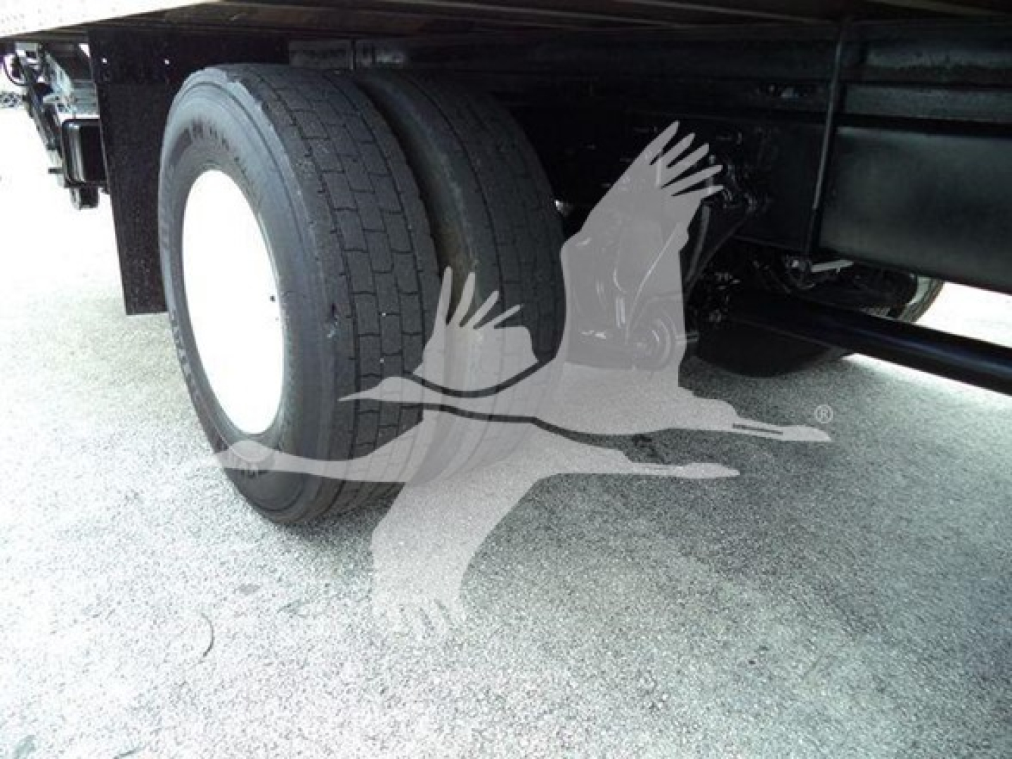 Truck chassis side showing dual rear tires and undercarriage with wheels and frame visible.