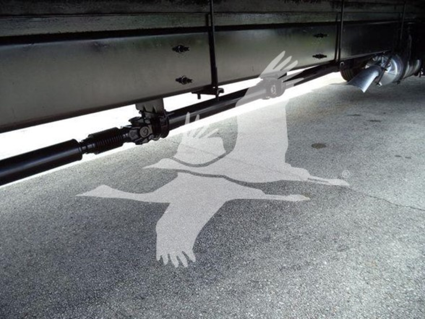 Underbody view of a box truck showing drivetrain driveshaft and undercarriage components.