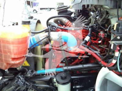 Truck engine bay showing coolant reservoir, hoses, and red engine components from a 2020 International MV.