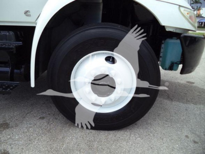 Truck front wheel and fender view showing white steel wheel, tire, and part of the cab; logo watermark present.