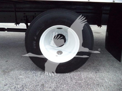 Truck wheel with white rim and black tire under a cargo box, side view of the undercarriage.