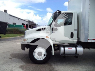 Truck side view showing cab and front wheel of a 2020 International MV box truck with white color and silver fuel tank.