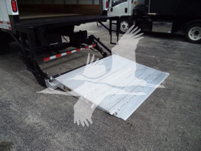 Platform/ramps of a truck with a metal lift gate deployed from the back of a flatbed unit. Mounted metal plate with ribbed surface and hydraulic lift mechanism visible.