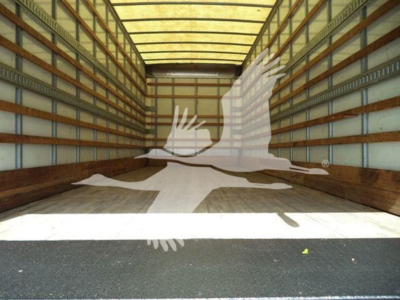 Empty truck trailer interior with wooden side rails and light roof; truck bed open at back.