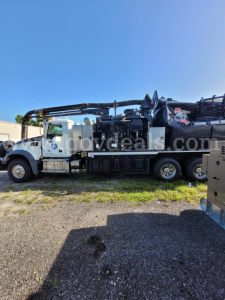 2017 Mack GU713 vacuum truck side view showing long hydraulic boom, cab, and equipment body with multiple labels; no legible text clearly visible on components.