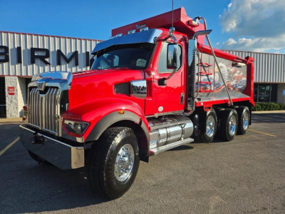 Dump truck with red cab and dump bed, Western Star 49X, front grille, dual rear axles, chrome fuel tanks, side steps, and warning lights.