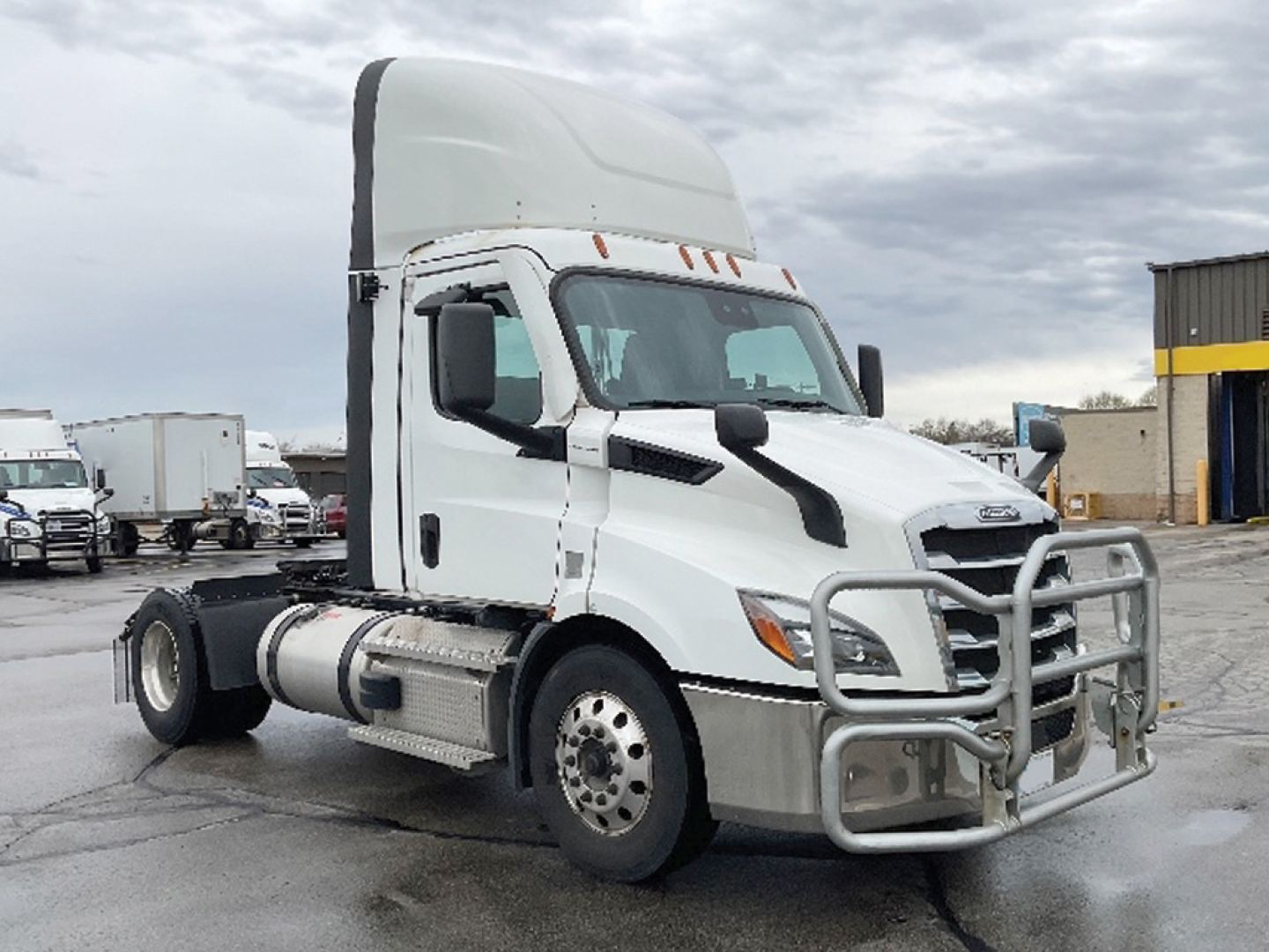 Freightliner Cascadia 116 daycab tractor in a dealership lot, white cab with grille guard and high sleeper