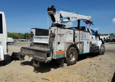 Ford F750 service truck with aerial lift in side view showing rear and crane equipment.
