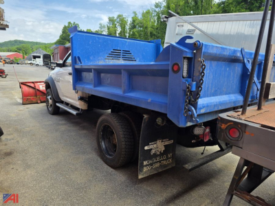 Dump truck bed and rear wheel area of a white Ram 5500 with a blue dump body and plow attachment visible.