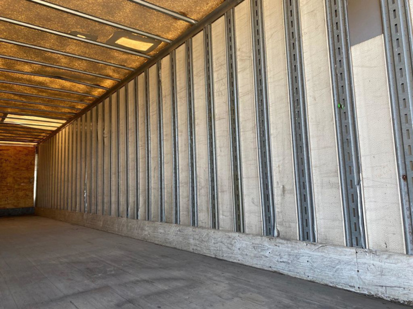 Trailer interior with metal wall studs and wooden floor showing cargo space