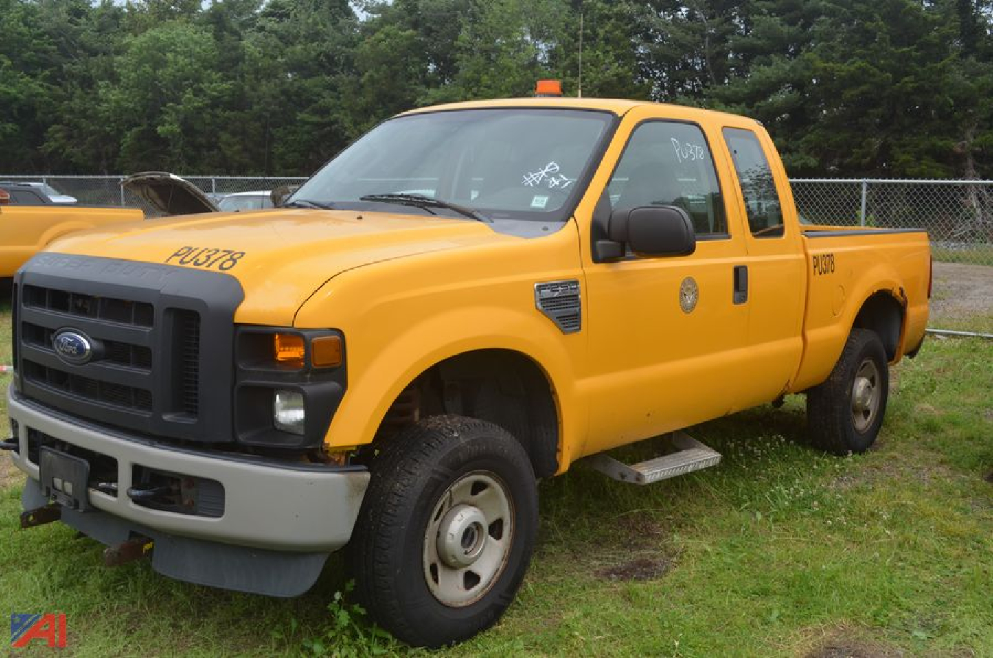 Ford F-250 Super Duty yellow extended cab pickup truck side view with black grille and orange emergency beacon on roof.