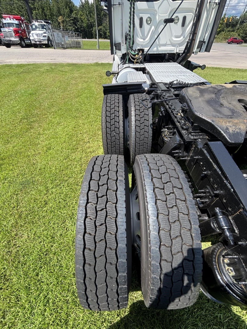 Freightliner Cascadia 126 rear view showing dual rear axles with tires and chassis, cab doorway, and side steps.