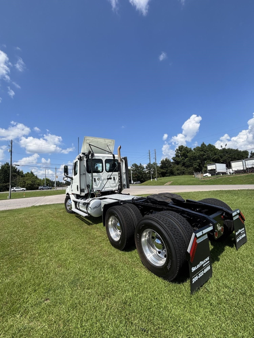Truck at an outdoor lot showing a Freightliner Cascadia 126 tractor from rear three-quarter view; dual rear axles, fifth wheel, mud flaps, and white cab with large mirrors.