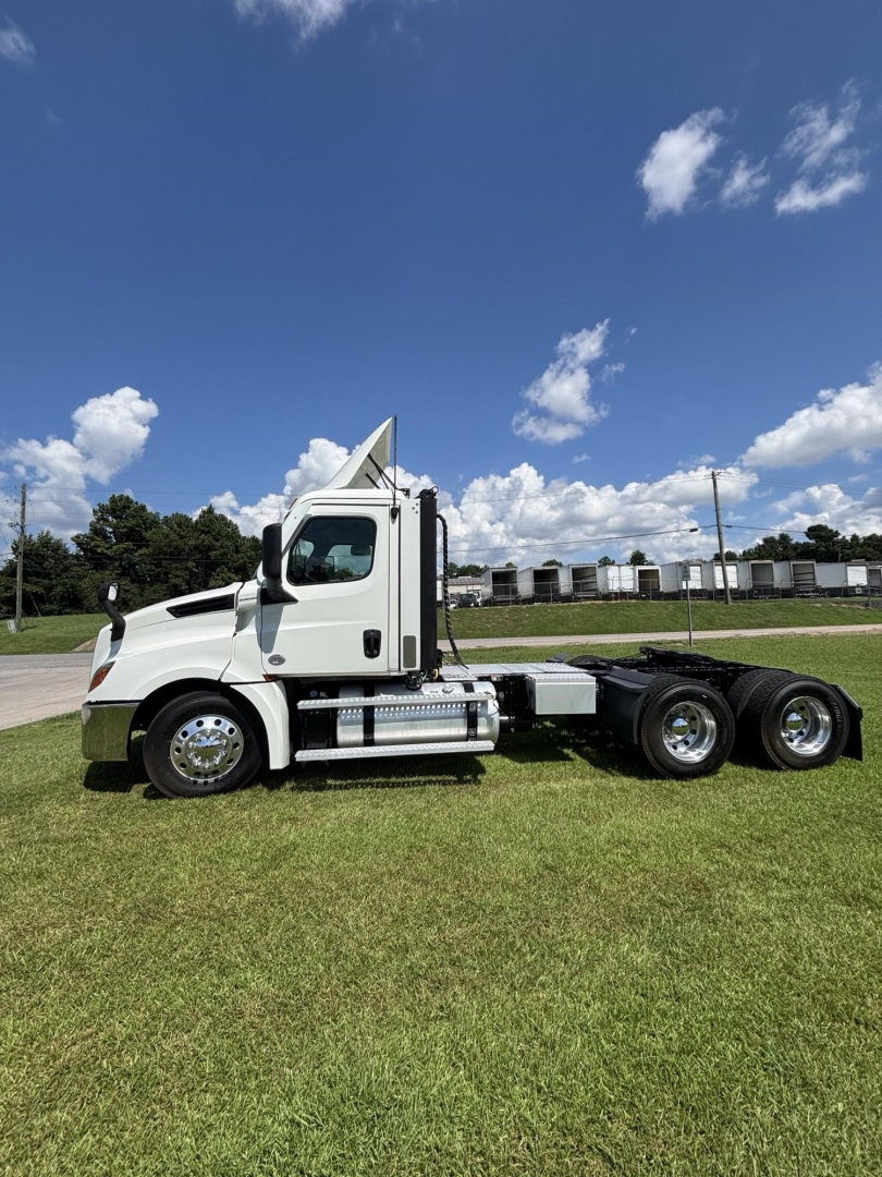 Truck chassis with cab of a 2021 Freightliner Cascadia 126 tractor, side view showing dual rear axles, chrome fuel tanks, and side steps.