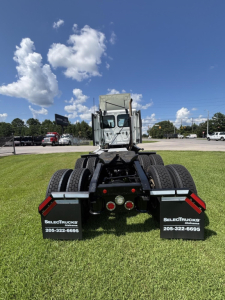 Rear view of a 2021 Freightliner Cascadia 126 truck chassis showing dual rear axles, black mud flaps with SelectTrucks branding, and tail lights.