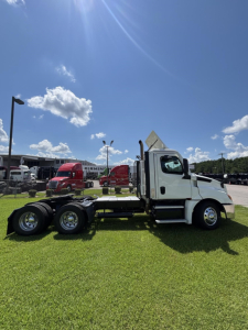 Freightliner Cascadia 126 day cab tractor in side view with chassis exposed and cab white, at a dealership lot.