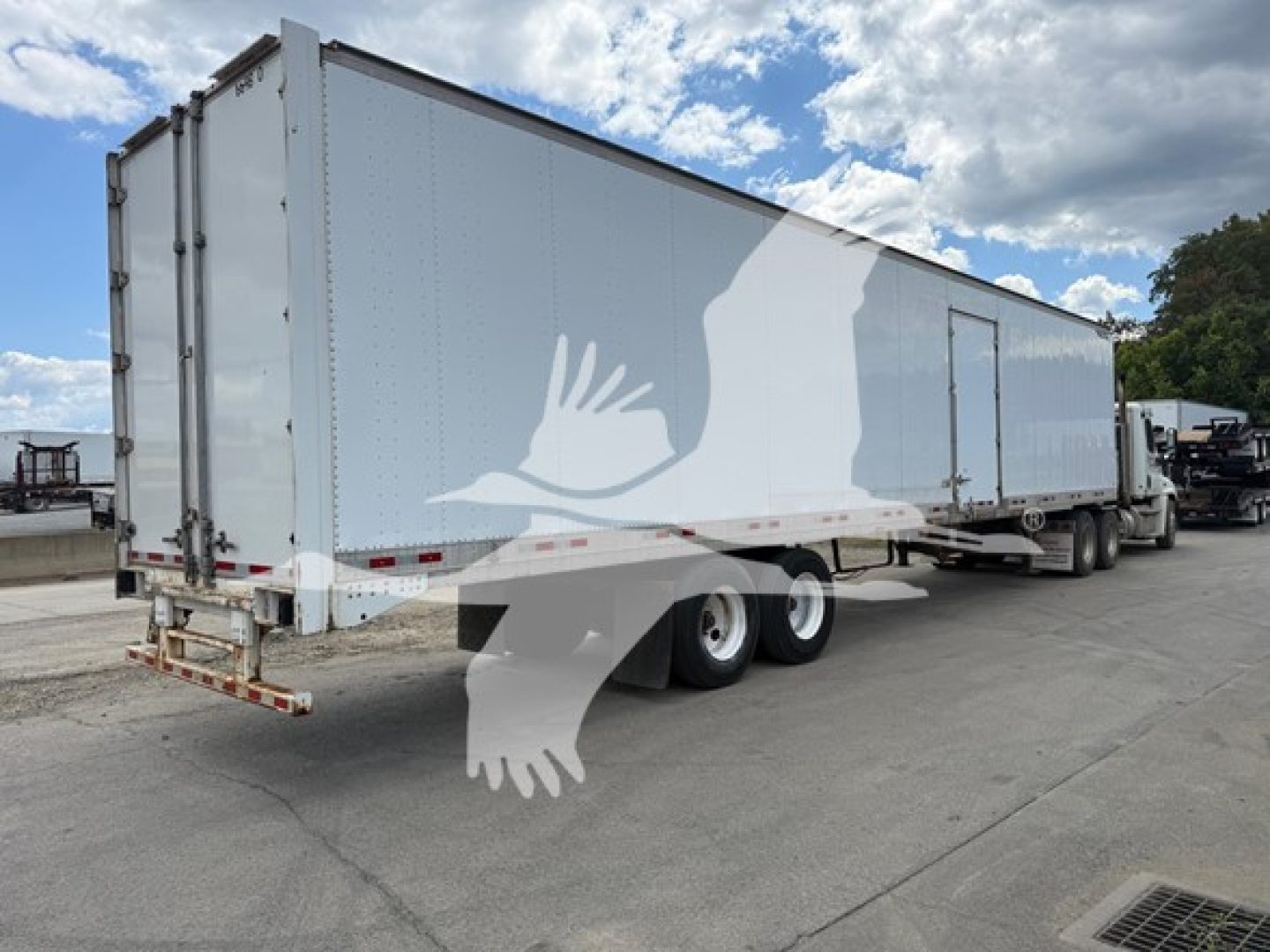 Great Dane swing door trailer with side door in a parking lot. Dual rear doors, white exterior with gray graphic of a flying bird. Tandem axle trailer.