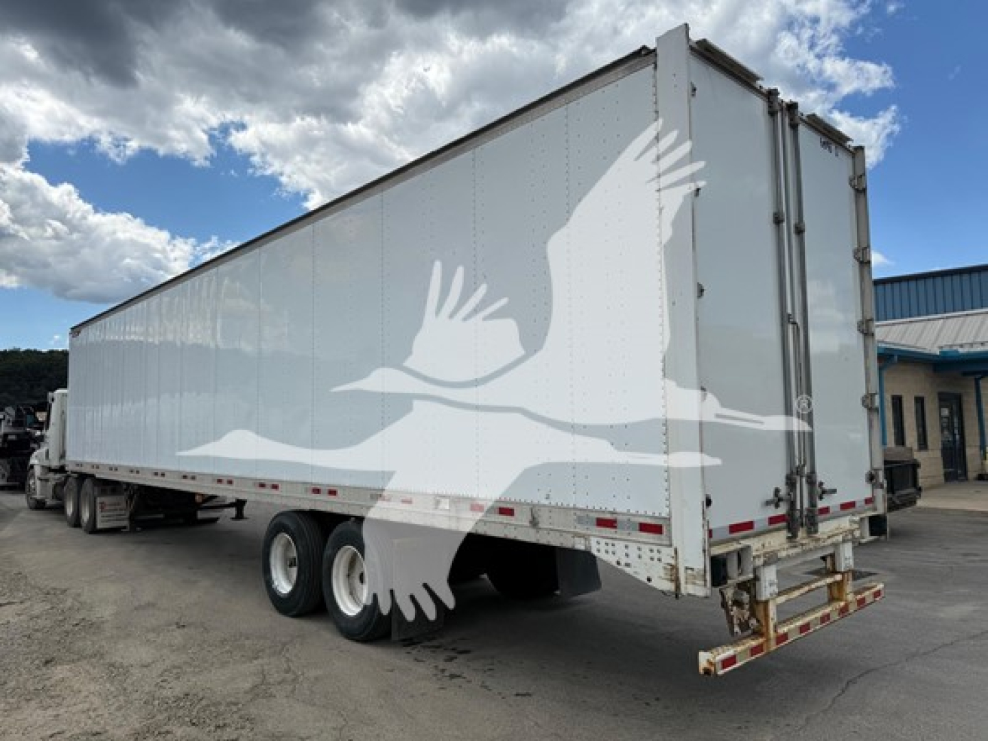 Great Dane swing-door trailer with side door showing rear doors and a white bird watermark in the side panel.