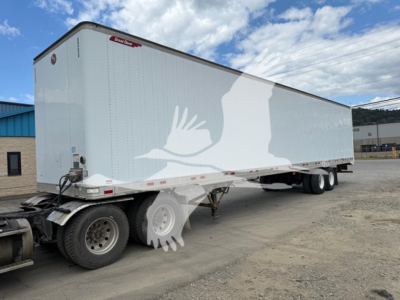Great Dane trailer with swing and side doors, long white exterior with logo silhouettes, dual rear axles, parked on lot.