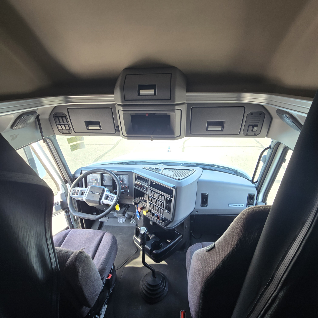 Truck cab interior view of a 2020 Mack Anthem showing steering wheel, dashboard, gear shifter, and overhead compartments.