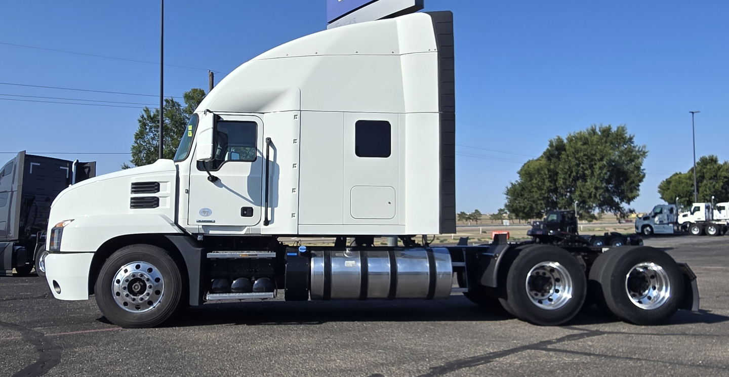 Truck side view of a white 2020 Mack Anthem sleeper cab with fuel tanks and rear axle configuration visible.