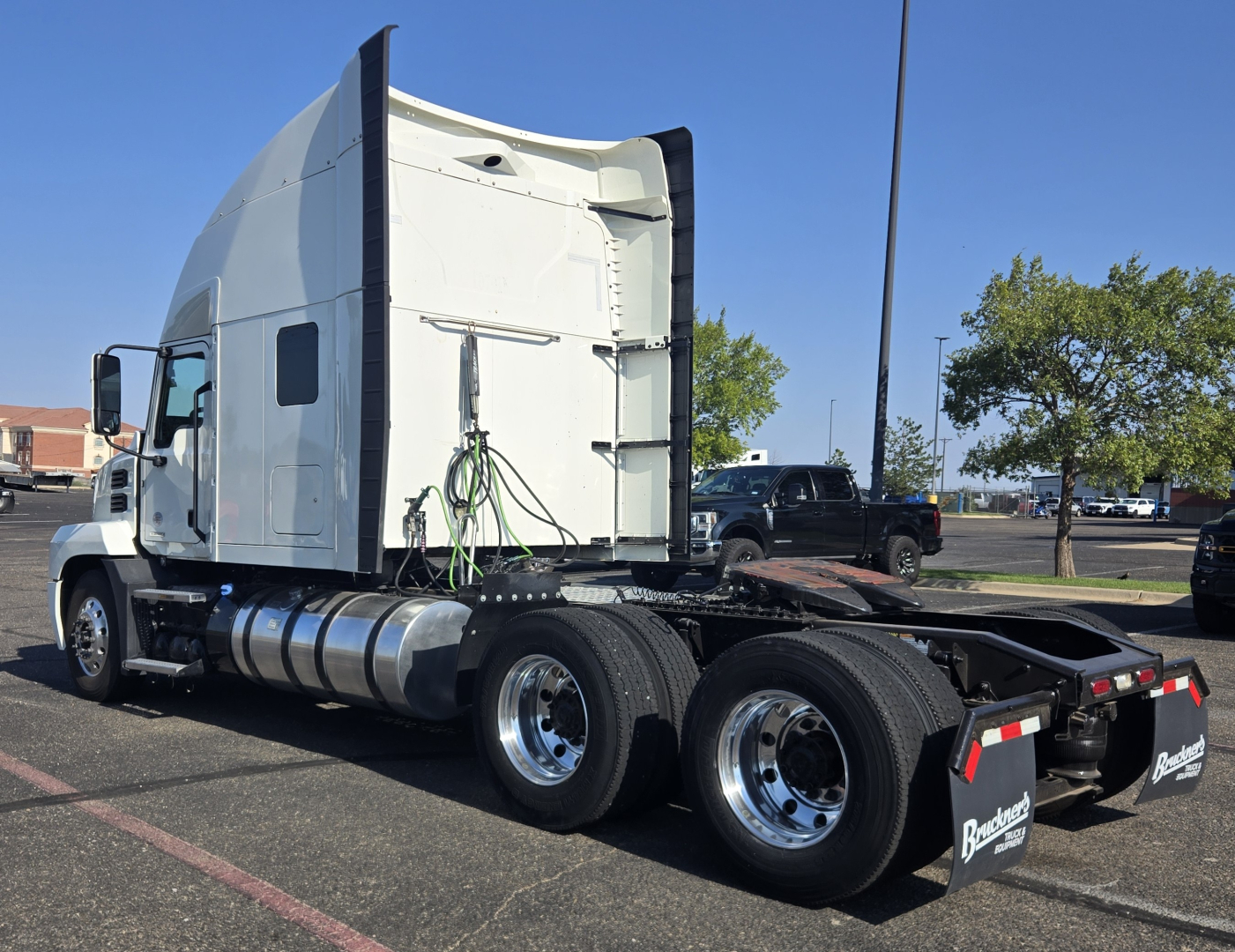 2020 Mack Anthem conventional sleeper tractor in a parking lot, side view showing rear chassis and dual rear axles with chrome wheels.
