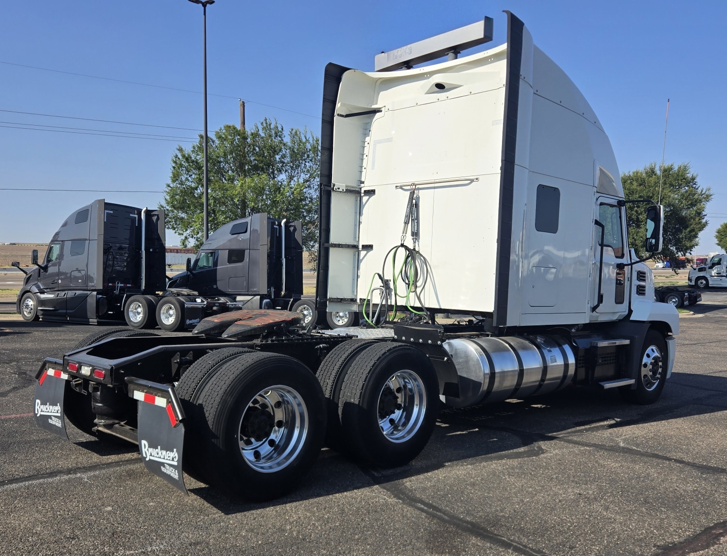 Truck tractor side rear view showing dual rear wheels and sleeper cab with fuel tanks and air lines
