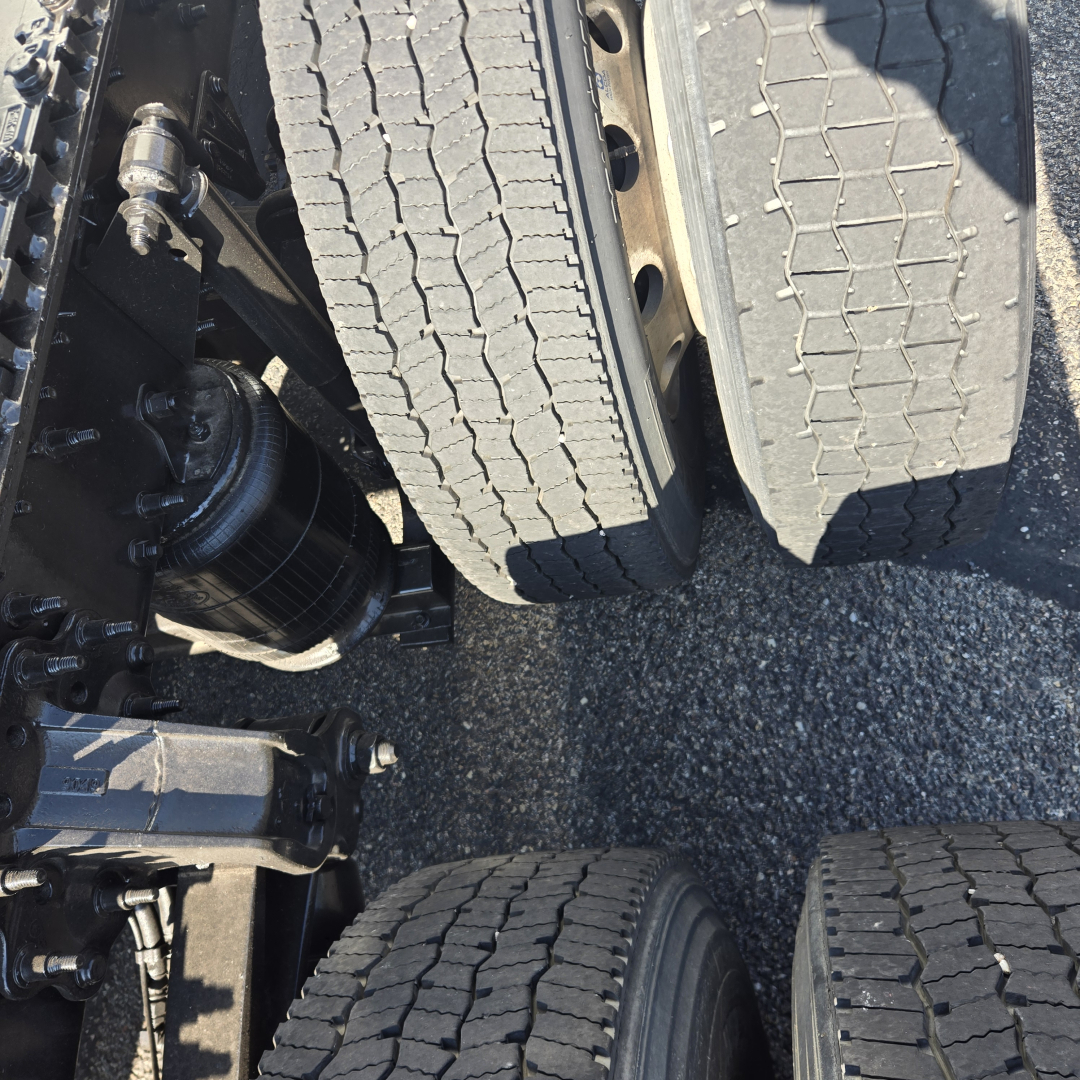 Truck axle view with dual rear tires and suspension components visible.