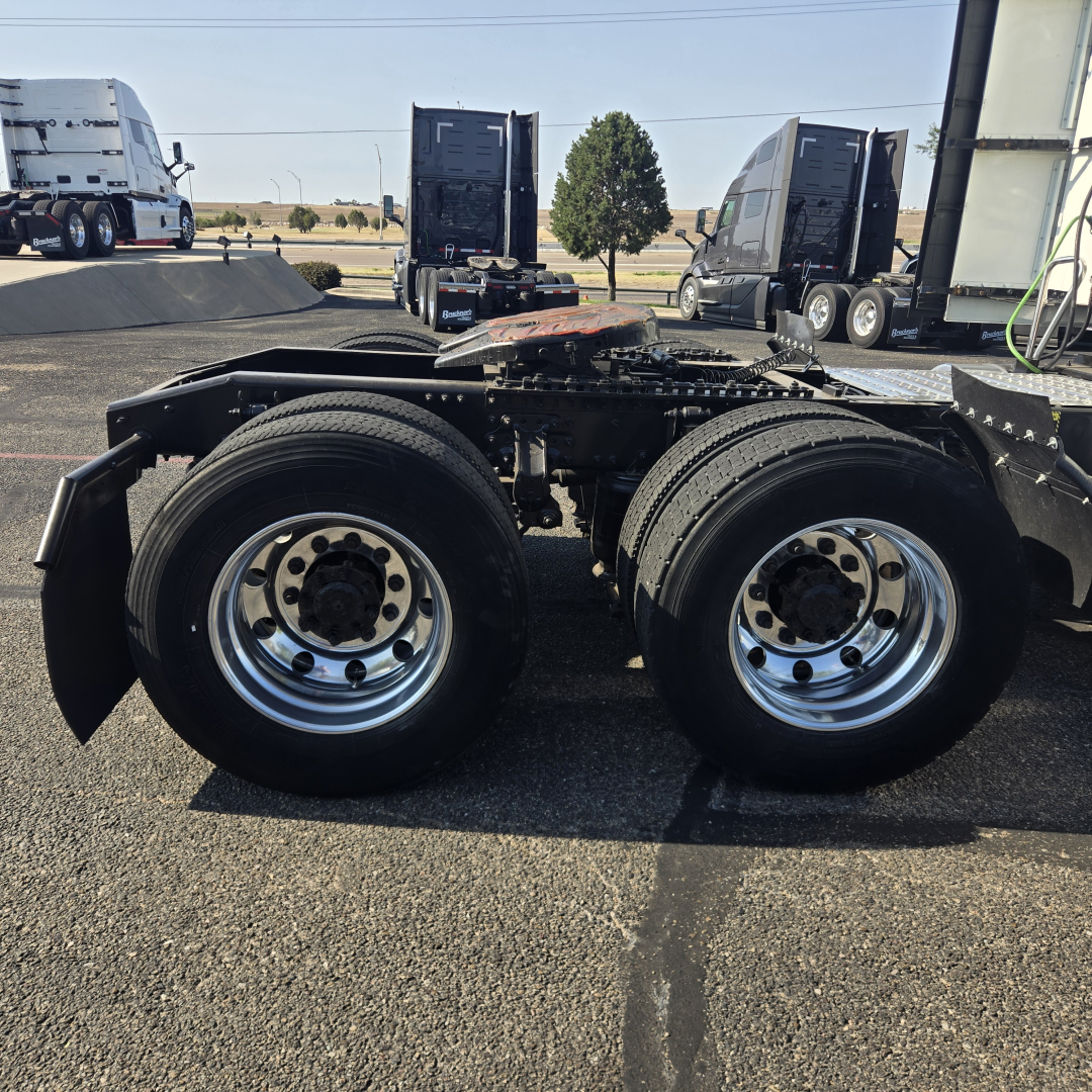 Tractor trailer chassis showing dual rear axles with polished steel wheels.