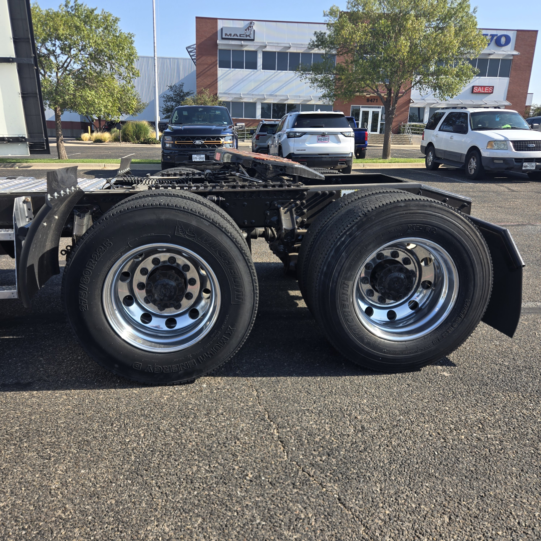 Twin rear axles and wheels of a Mack ANTHEM truck chassis in a dealership lot.