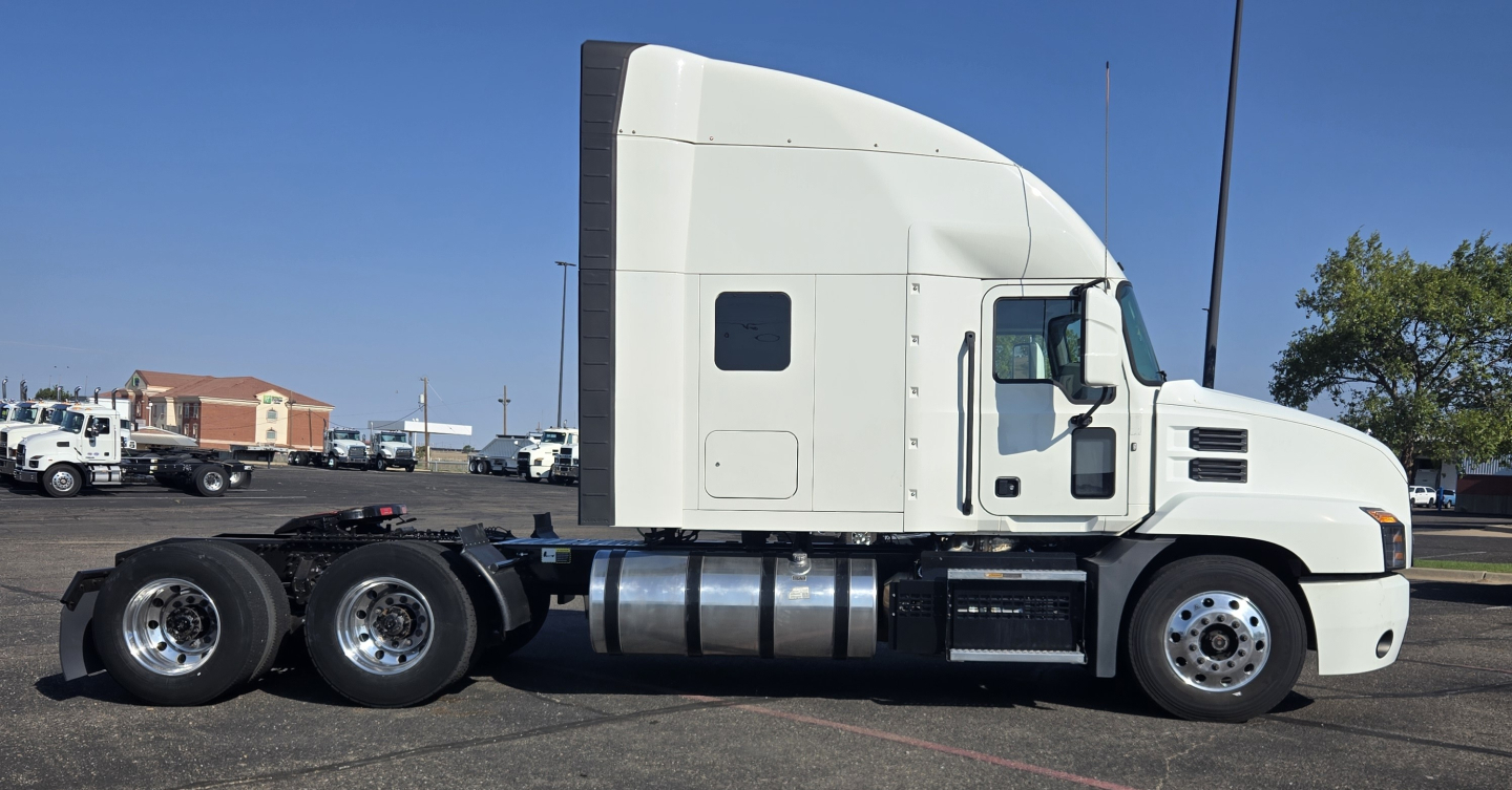 Truck side view of a 2020 Mack Anthem sleeper cab showing the white tractor with three rear axles and fuel tanks