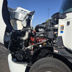 Mack Anthem truck engine bay visible with hood open, showing engine components, hoses, and wiring in front section.