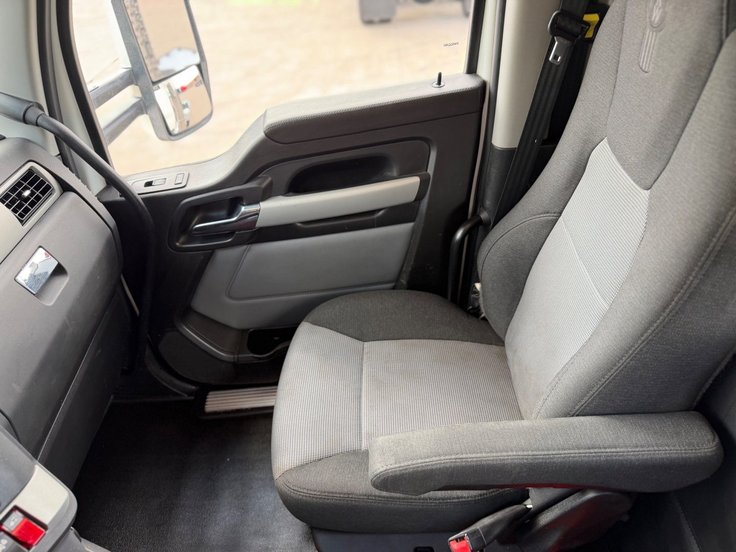Kenworth T880 cab interior showing front passenger seat and door panel with armrest and window controls.