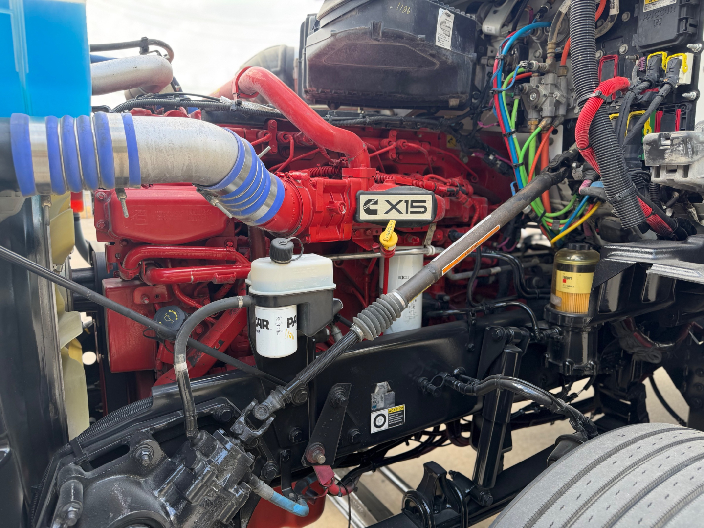Kenworth T880 engine bay showing EX15 badging on red engine and various hoses and reservoirs.