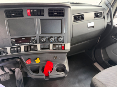 Kenworth T880 dashboard and center console showing controls, radio, climate knobs, cup holders, and ignition area.