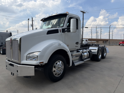 Kenworth T880 conventional daycab truck side view showing chrome front bumper, dual rear axles, white cab, and fuel tanks.