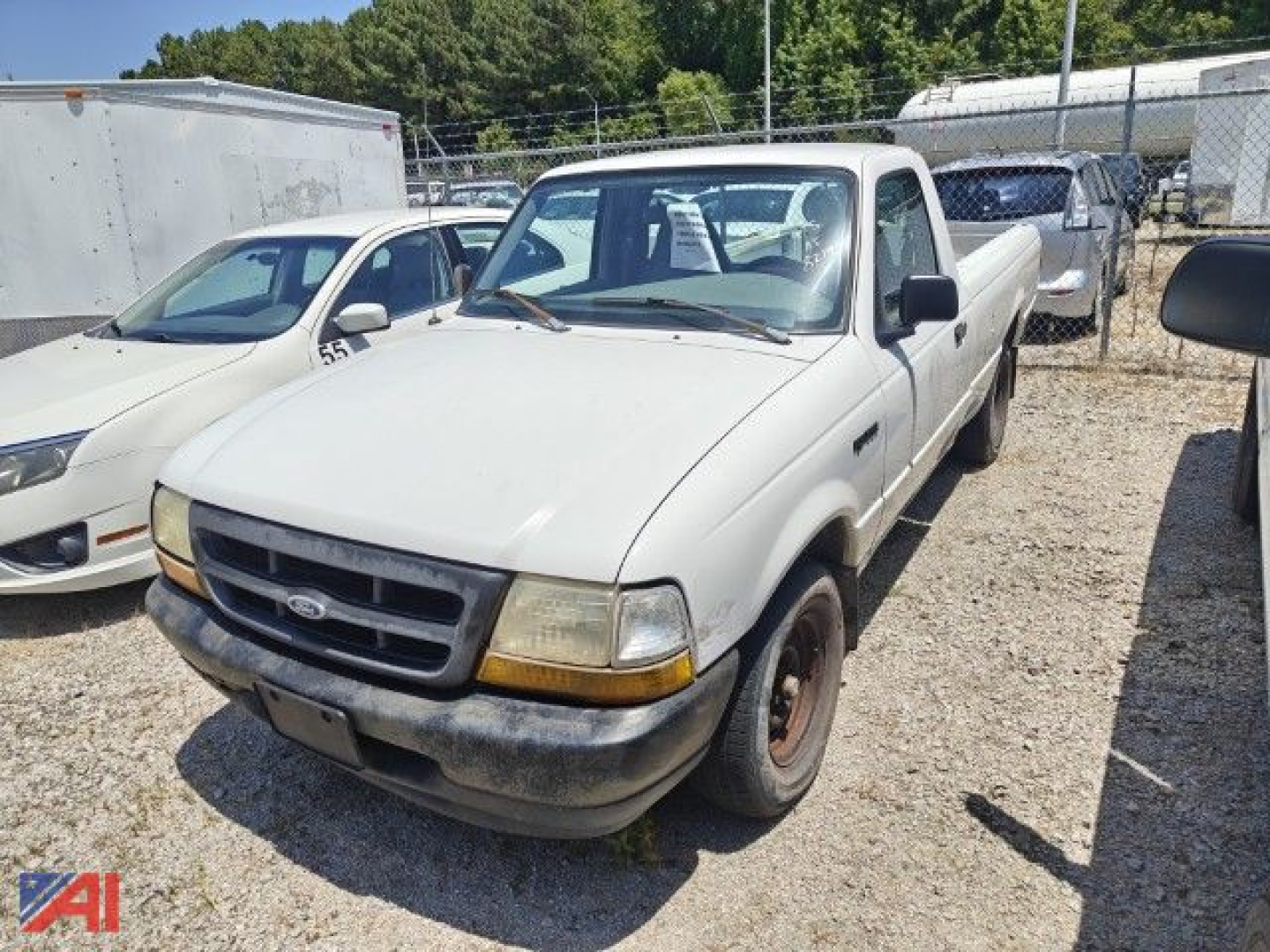 Ford Ranger pickup truck in a used lot, white cab, long bed, front view with black bumper and yellowing headlights.
