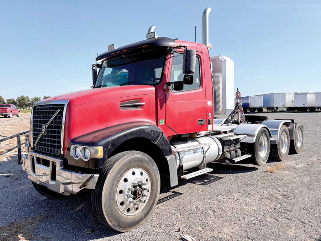 Volvo VHD 300 conventional daycab truck in red with dual rear axles and chrome exhaust stack.