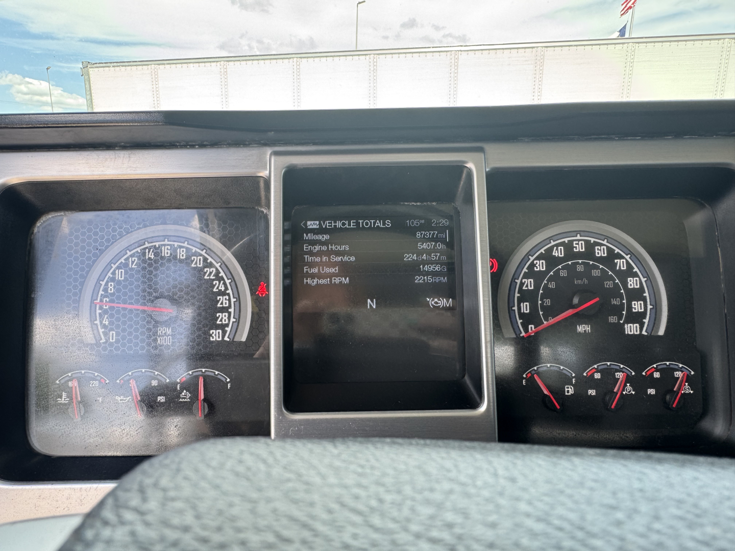 Dashboard of a 2023 Mack GR64B roll-off showing instrument cluster with speedometer and tachometer, center screen displaying vehicle totals including miles and hours.