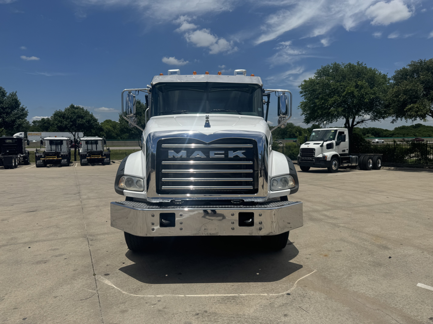 Front view of a white 2023 Mack GR64B truck showing large chrome grille with 'MACK' lettering, chrome bumper, and dual headlights.